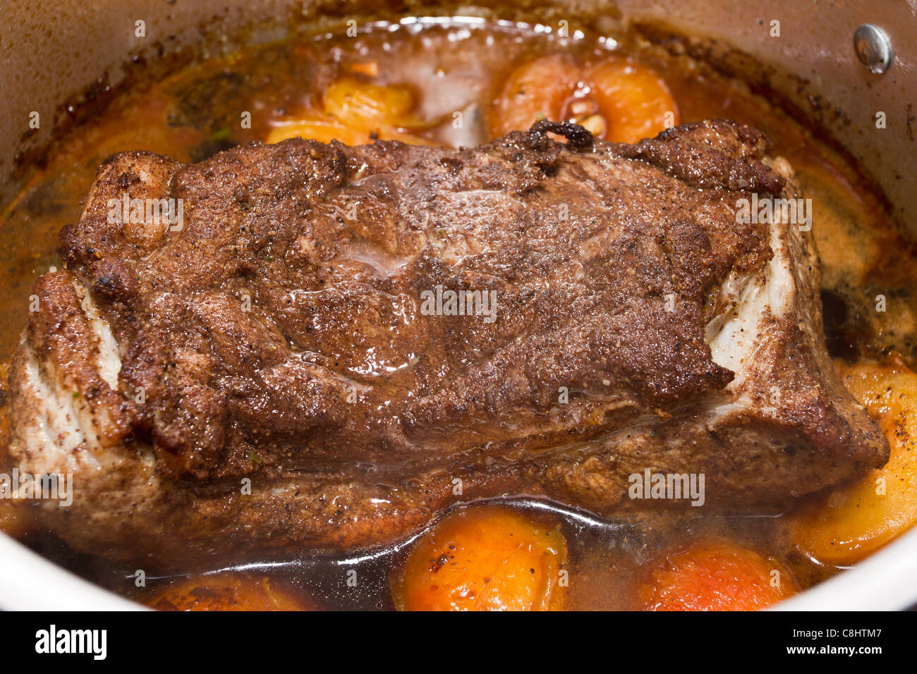 Asian spiced pork with plums simmering in silver cooking pot. Stock Photo