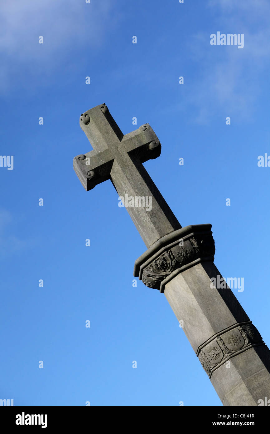 Stone cross on top of a church in Scotland, UK, with blue sky backdrop Stock Photo