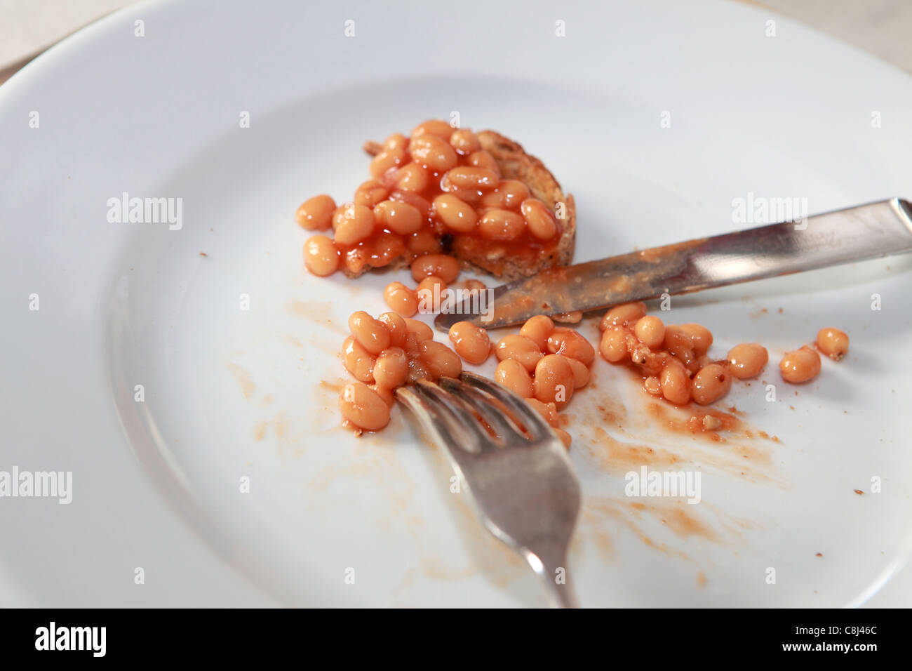 Plate, nearly finished lunch of baked beans, showing knife and fork