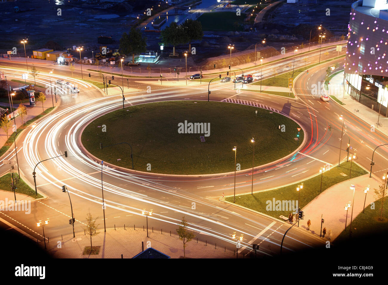 Roundabout in a city. At night, lights of cars around the circle. Controlled by traffic lights. Stock Photo