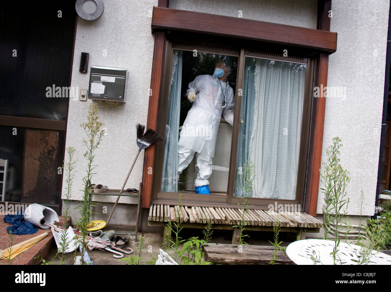 A man locks windows of the living room after briefly returning to his home in Okuma about 1.5 km from the No. 1 nuclear plant Stock Photo