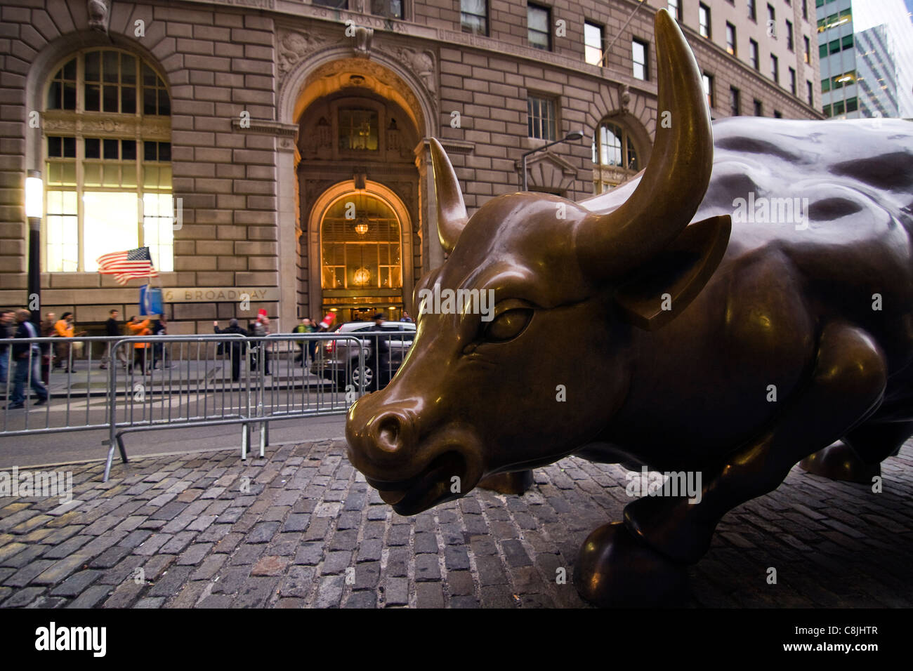 Financial District Bull Statue surrounded by barricades as protesters with US flags walk on the sidewalk on Broadway in New York Stock Photo