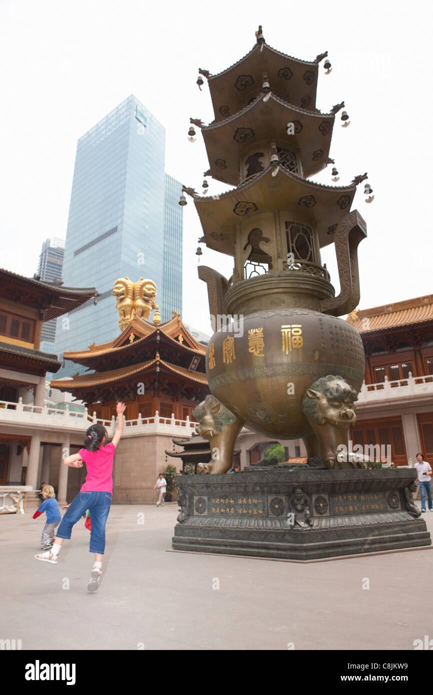 Girl throwing coin into cauldron Jing'an temple; Shanghai; China Stock Photo