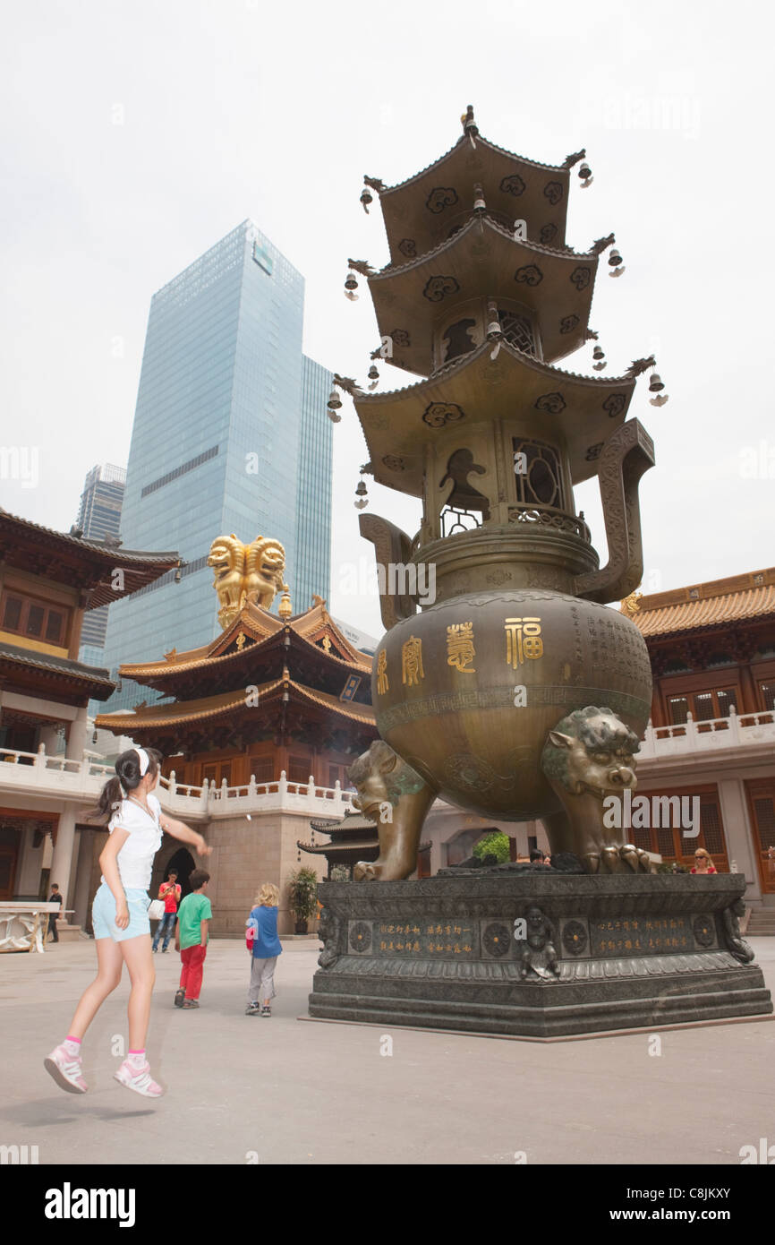 Girl throwing coin into cauldron Jing'an temple; Shanghai; China Stock Photo