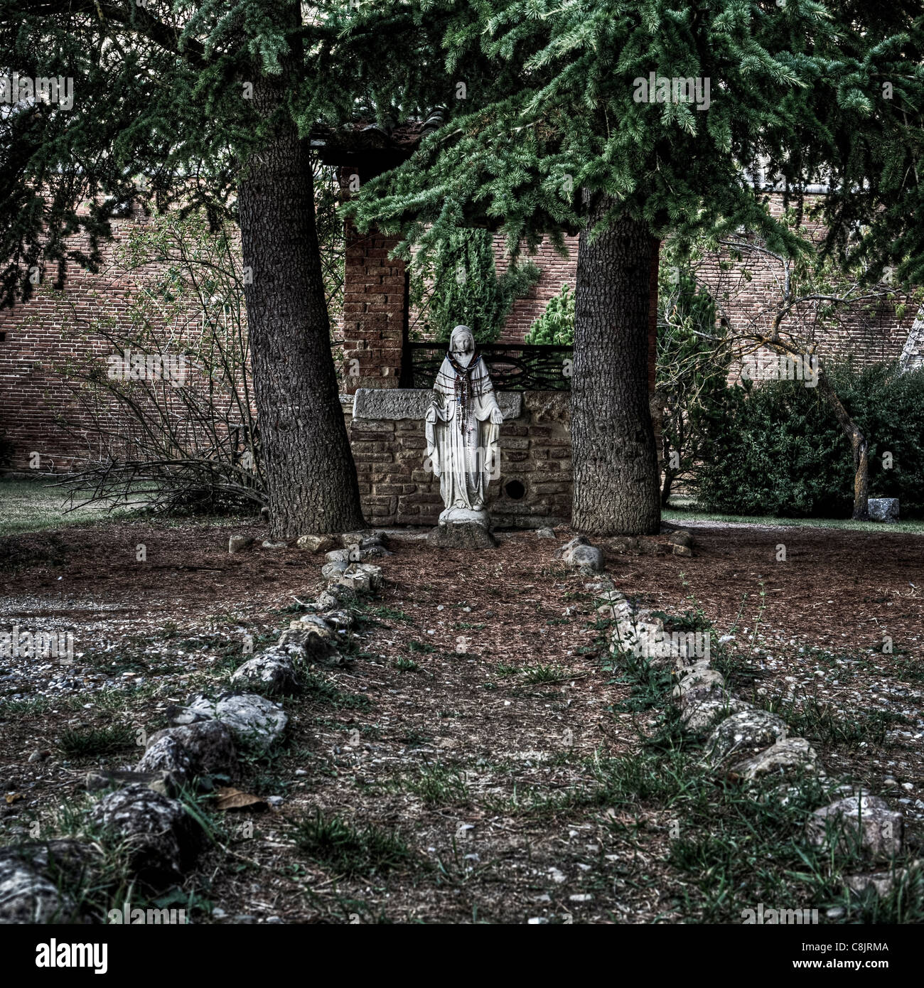 an old Madonna statue with rosaries in the garden of a monastery in Italy Stock Photo