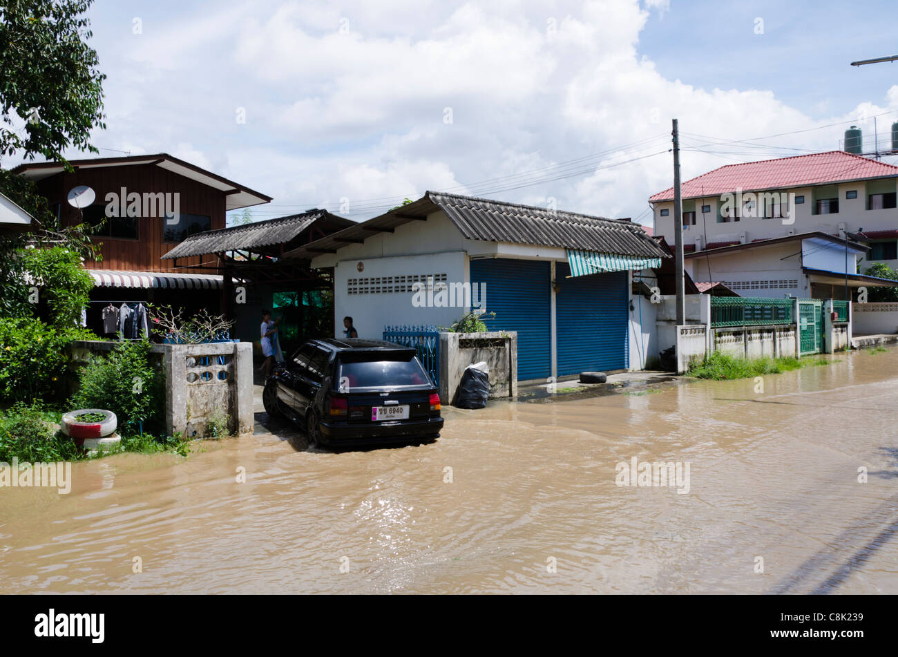 Car turns into driveway of house from flooded street at Koh Klang in Chiang Mai Thailand Stock Photo