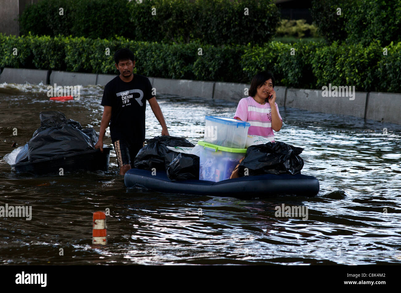 Thai refugees wade through the flood, one talking on a cel phone, at Don Muang airport, Bangkok, Thailand, South East Asia. credit: Kraig Lieb Stock Photo