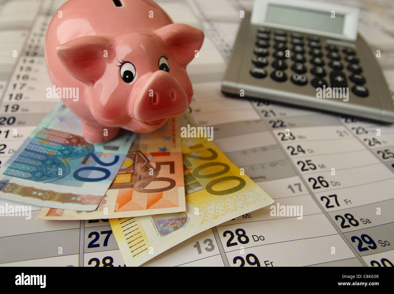 A Piggy Bank with calculator and money situated on a callender Stock ...
