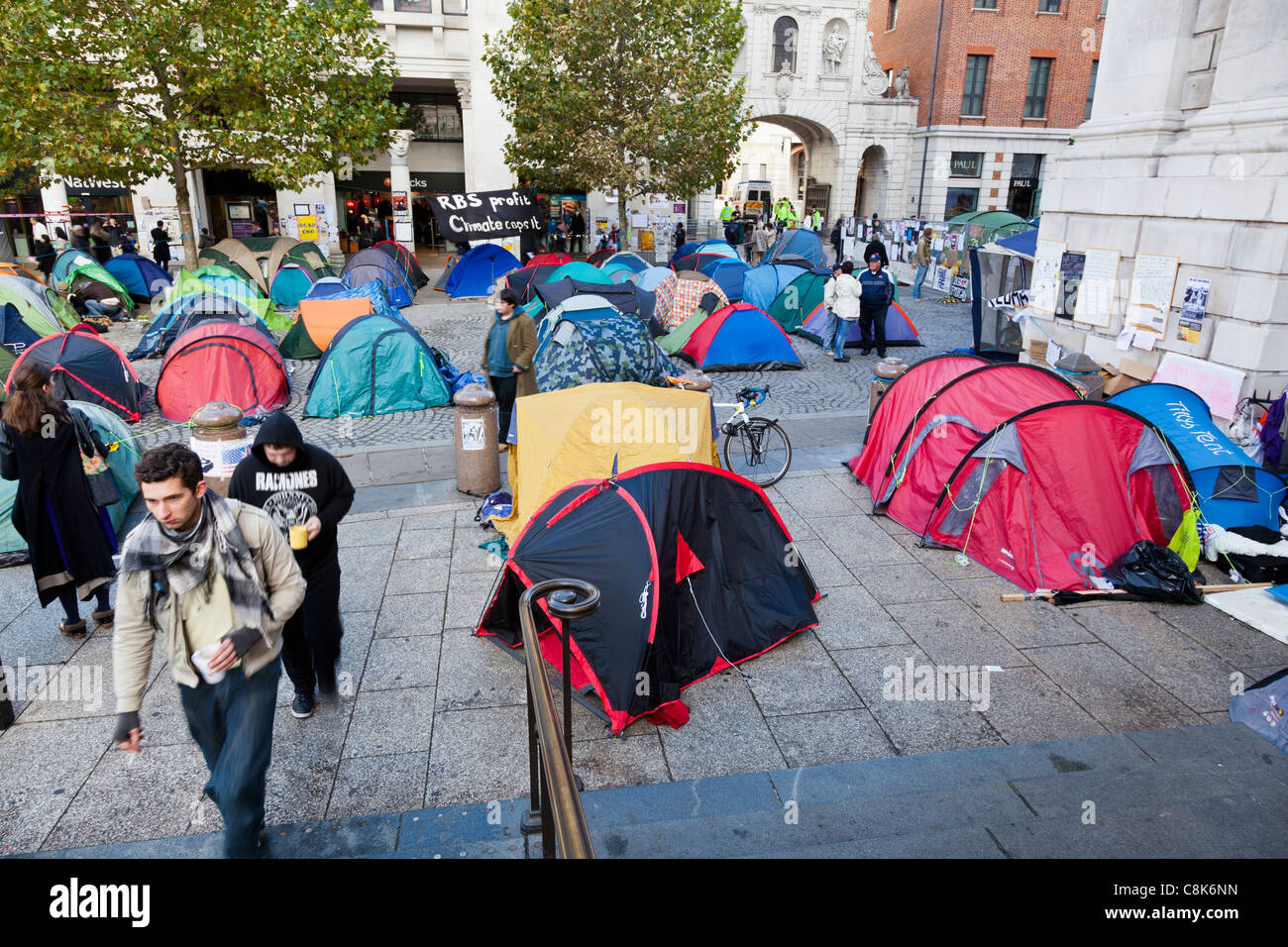 People pass between anti-capitalist protesters' tents outside St Paul's Cathedral, London, October, 2011. Stock Photo