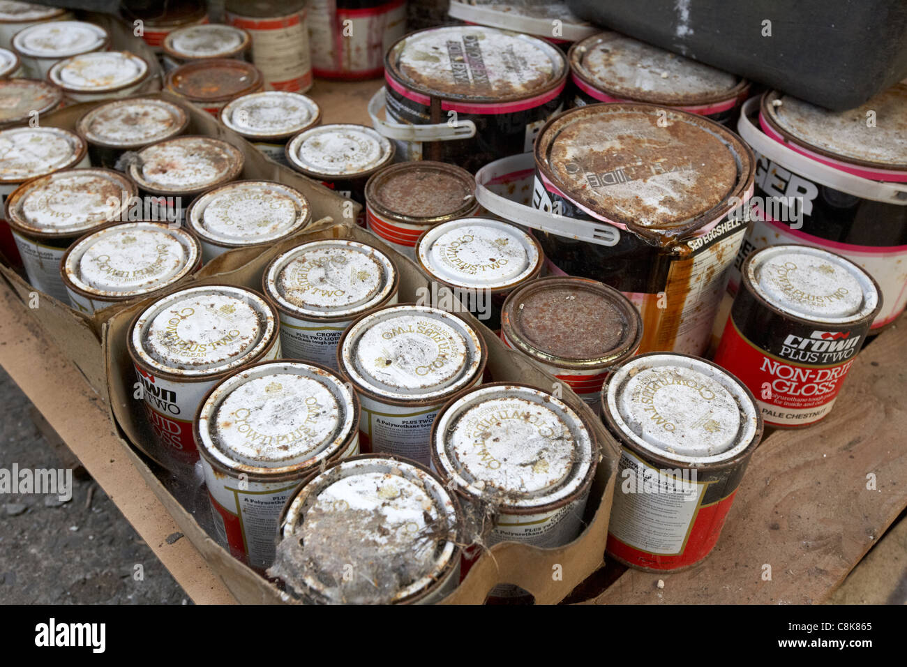 pile of old crown tins of paint rusting and covered in dirt in an old factory warehouse unit