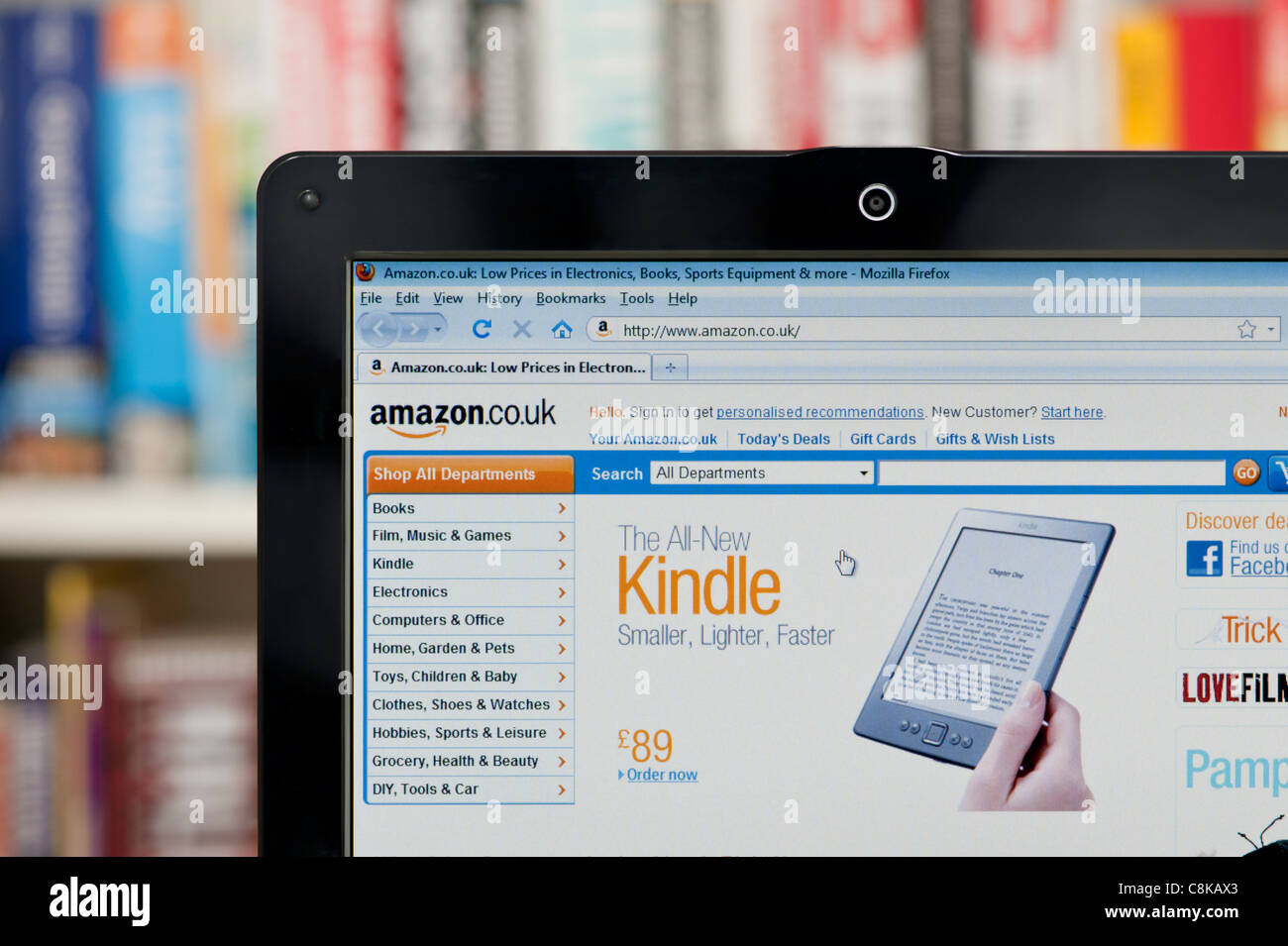 The Amazon website shot against a bookcase background (Editorial use only: print, TV, e-book and editorial website). Stock Photo