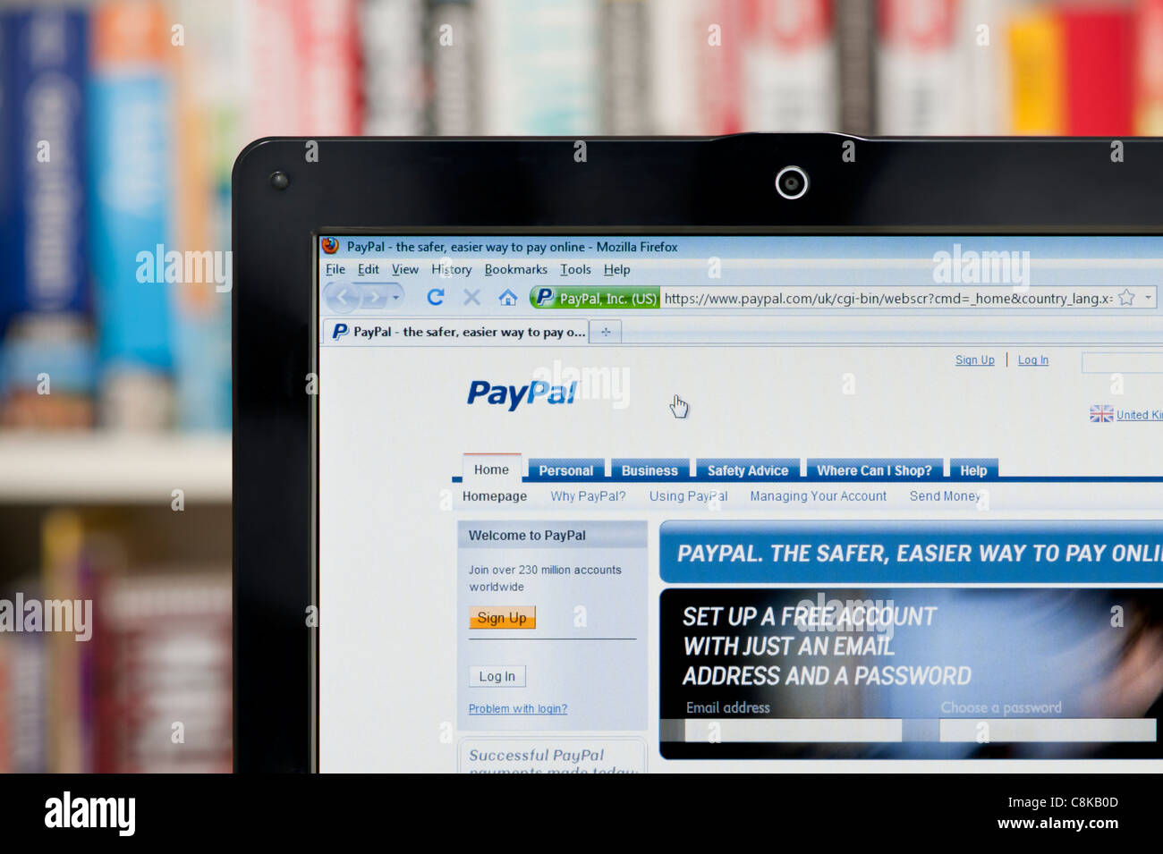 The PayPal website shot against a bookcase background (Editorial use only: print, TV, e-book and editorial website). Stock Photo