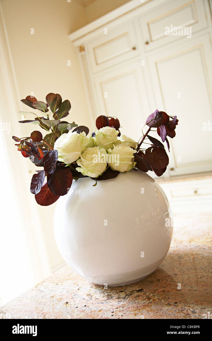 Large white vase in a kitchen with flowers. Stock Photo