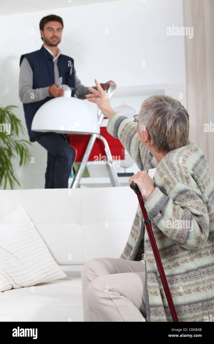 Young man putting up a light for an elderly woman Stock Photo