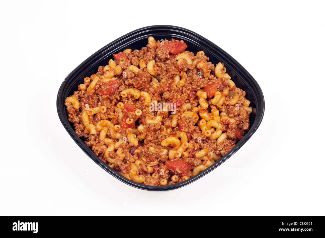 Takeaway tin of cooked macaroni and beef with tomatoes on white background, cutout. Stock Photo
