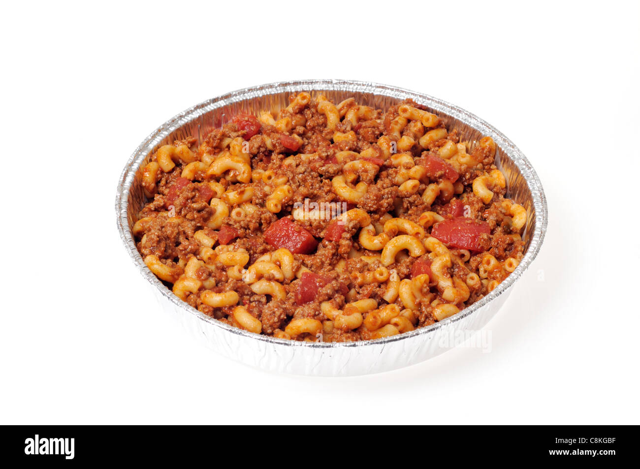 Takeaway tin of cooked macaroni and beef also called American Chop Suey with tomatoes on white background, cutout. Stock Photo