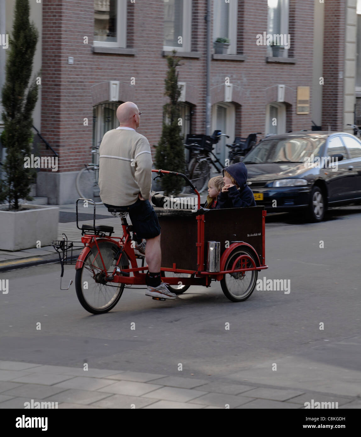 man transporting small children using cargo carrrier bike trike