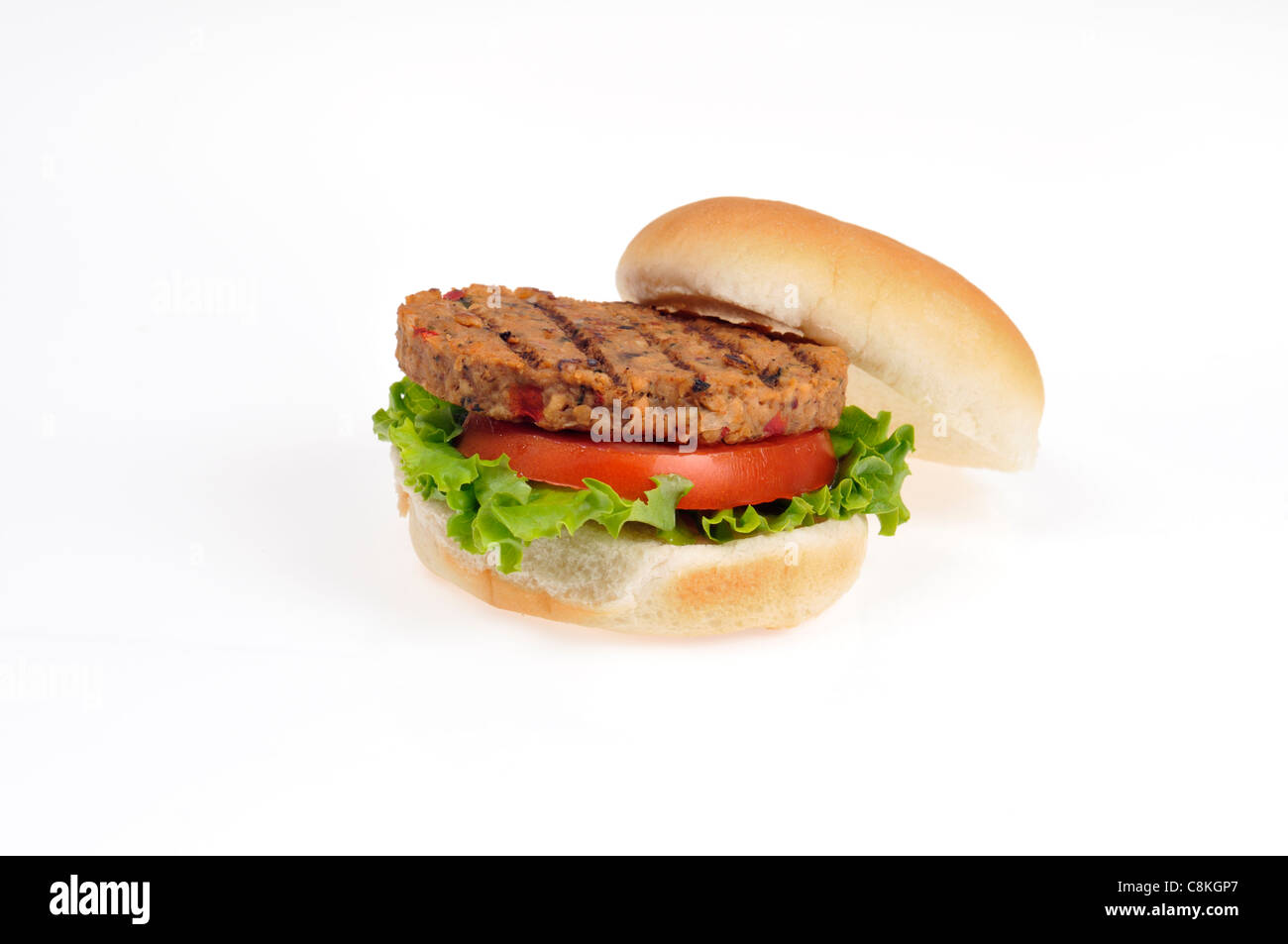 Open grilled vegan vegetarian veggie burger with lettuce and tomato in bread roll on white background cutout. Stock Photo