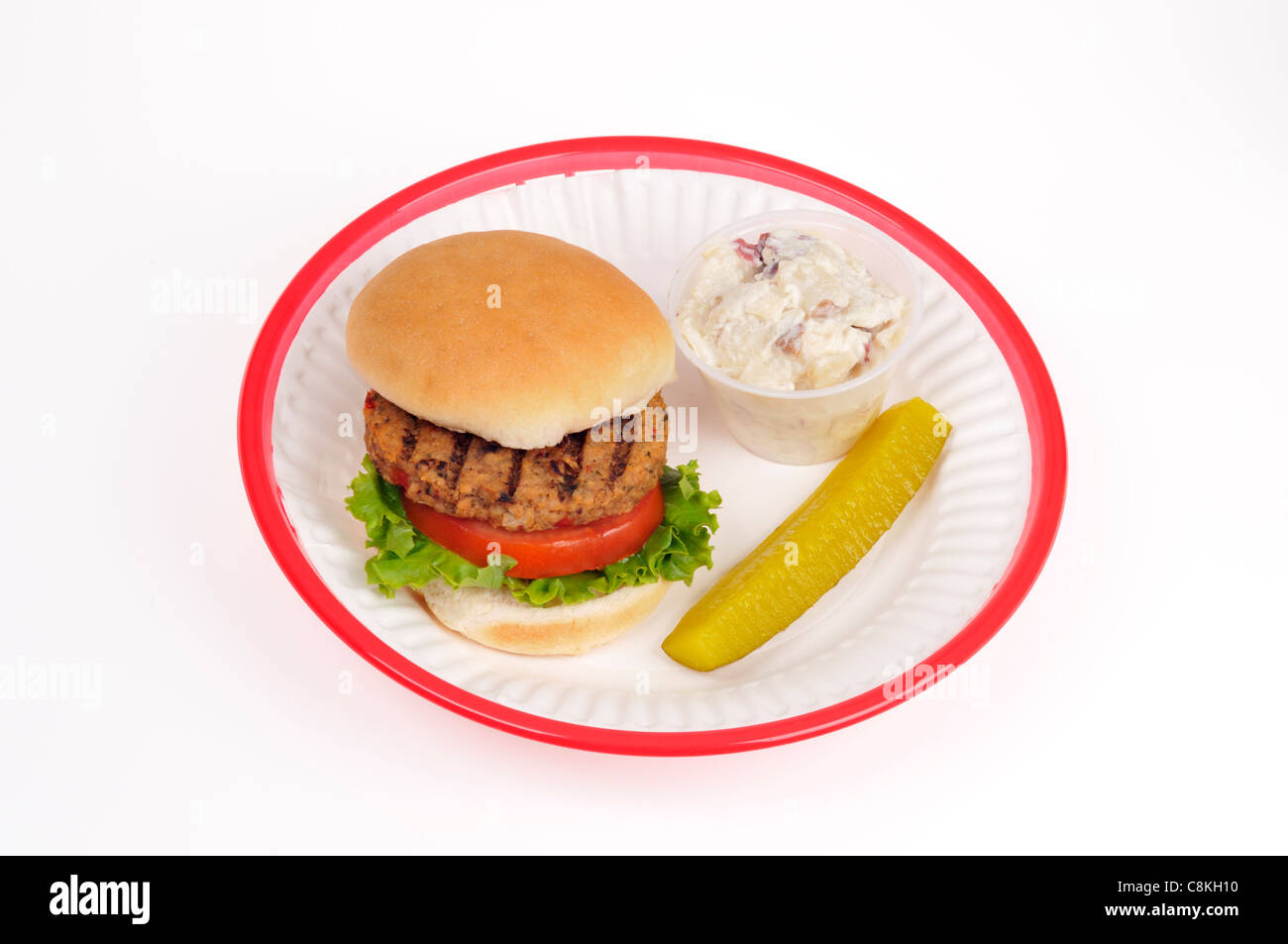 Grilled veggie burger with lettuce and tomato in bread roll in a red retro plastic basket on white background, cutout. Stock Photo