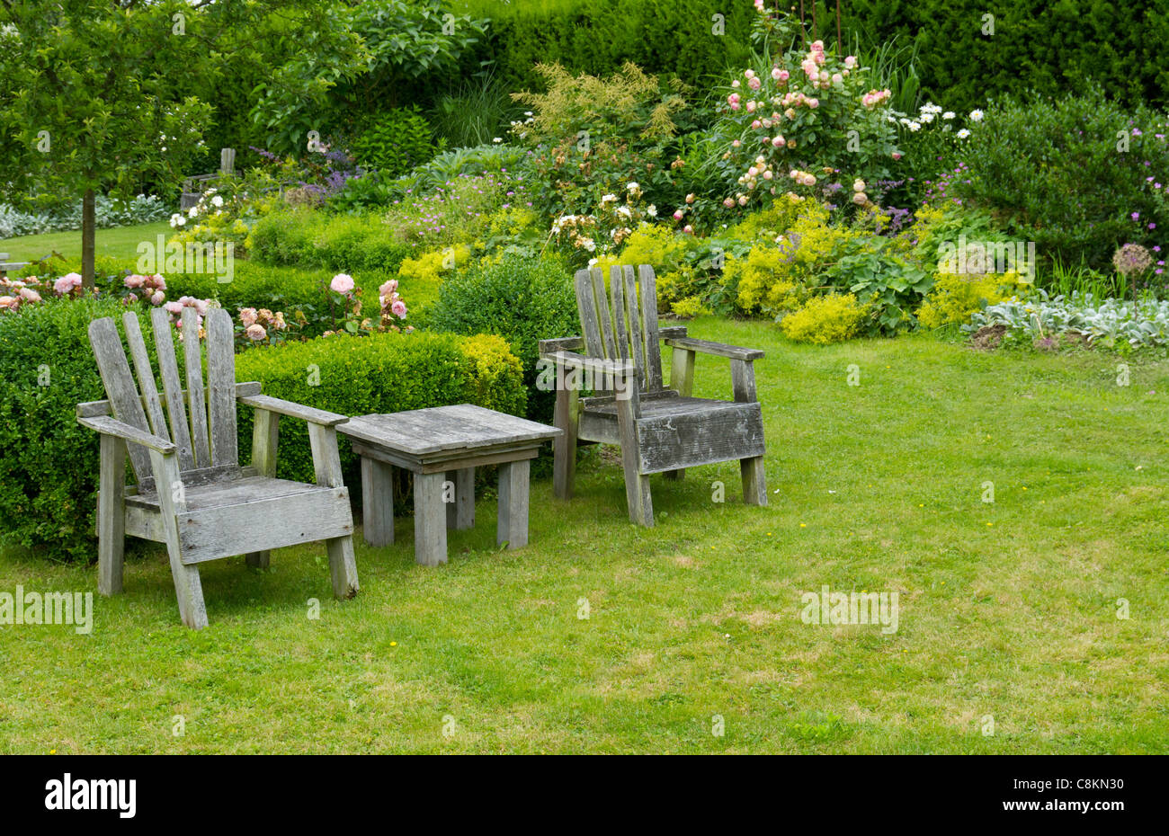 A pair of chairs and small table in the garden Stock Photo - Alamy