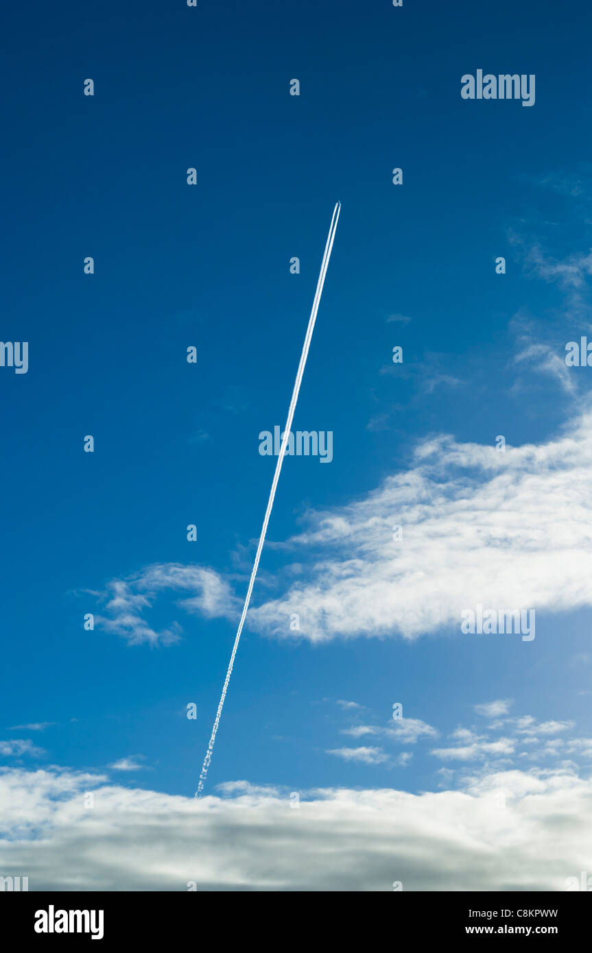 Jet plane with long contrail turning into rings at end Stock Photo