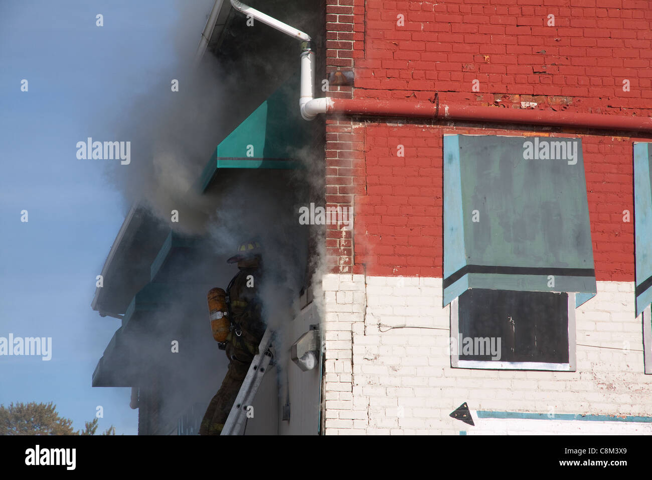 Firefighters entering second floor of burning commercial building fire Detroit Fire Department Detroit Michigan USA Stock Photo