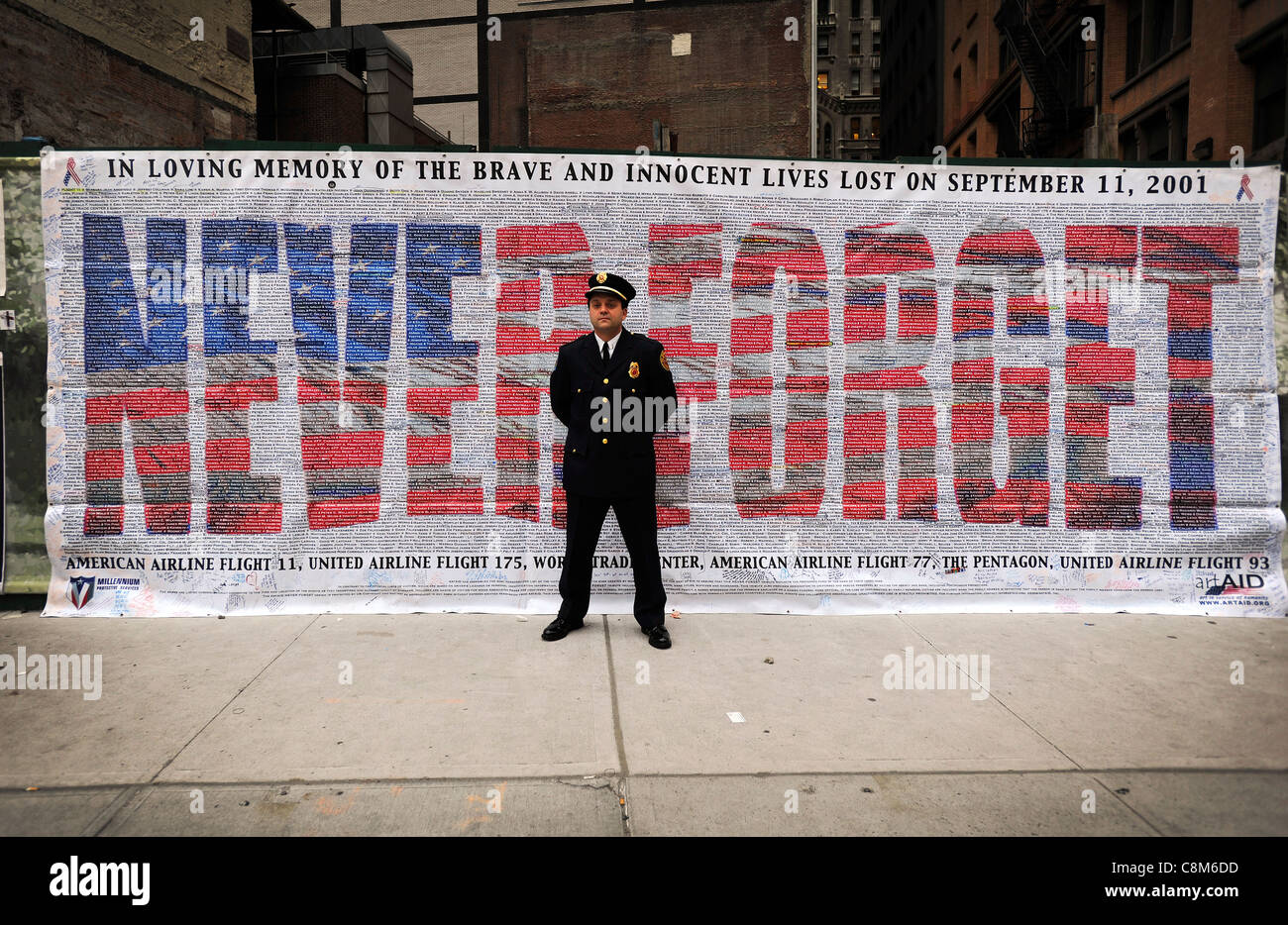 A firefighter stands in front of a 'Never Forget' banner at Ground Zero in New York on the tenth anniversary of the 9/11 attack Stock Photo