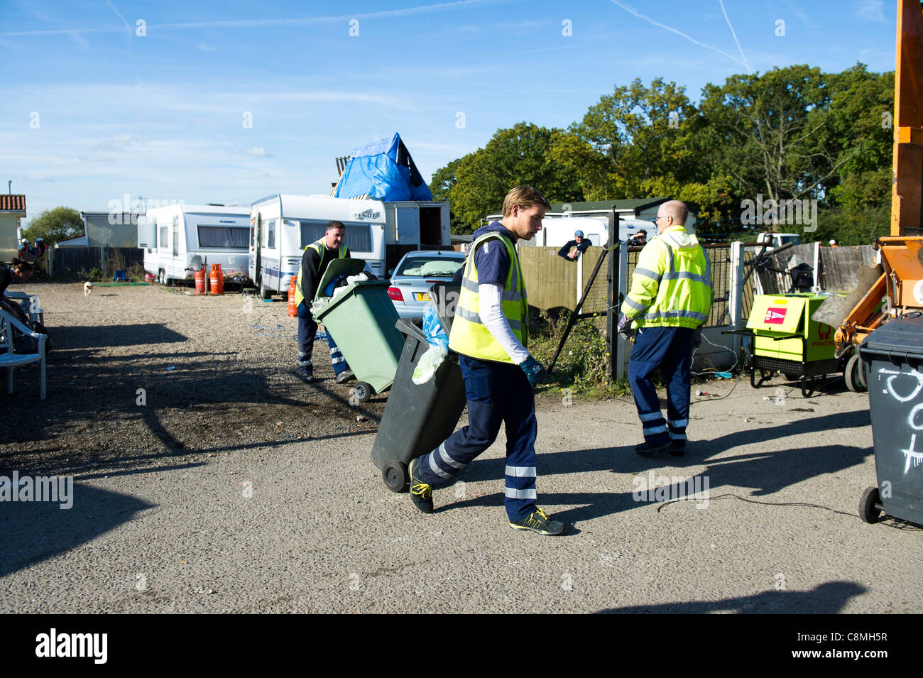 Refuse workers from Basildon Council in Essex working at rear of dust cart loading and emptying wheely (wheeled) bins into rear. Stock Photo