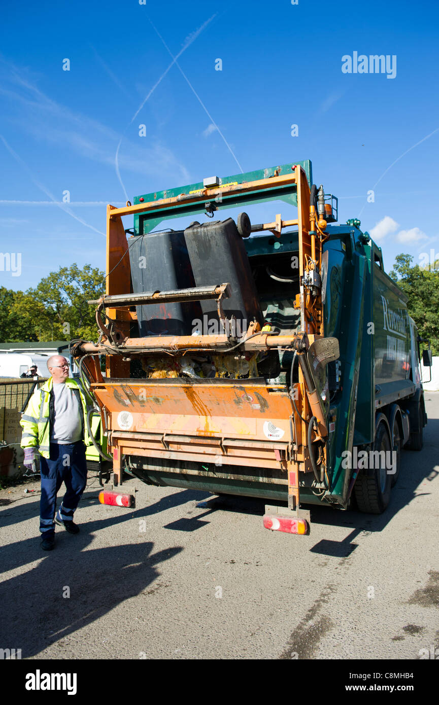 Refuse workers from Basildon Council in Essex working at rear of dust cart loading and emptying wheely (wheeled) bins into rear. Stock Photo