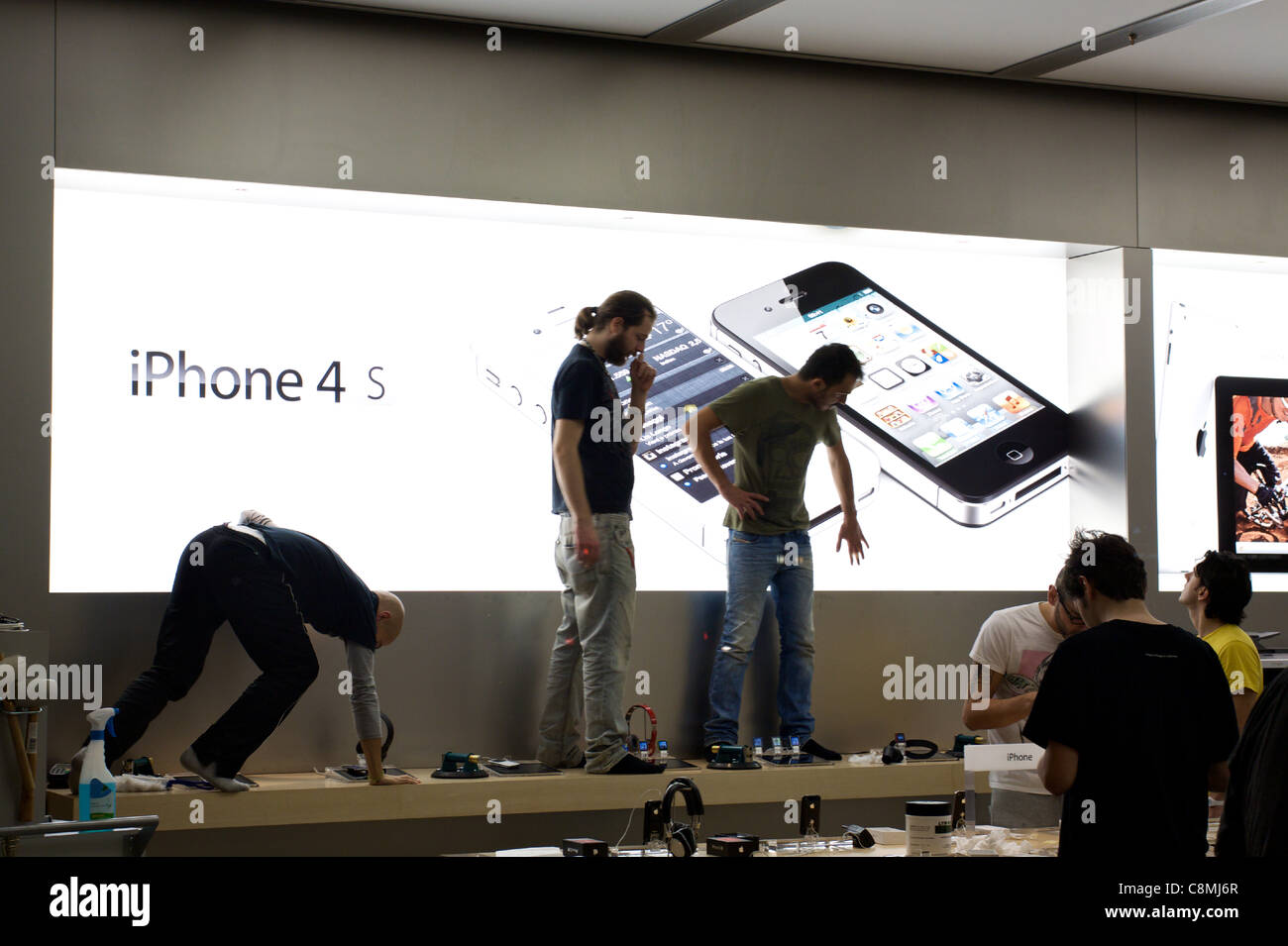 Apple Store iPhone 4s queue: Apple employers are adjusting the iPhone 4s  banner for the day after Stock Photo - Alamy