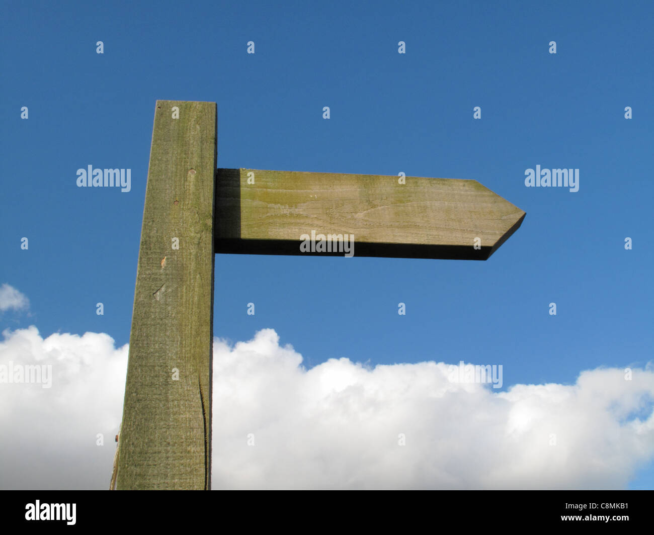 An blank wooden signpost against a blue sky with a bank of clouds. Stock Photo