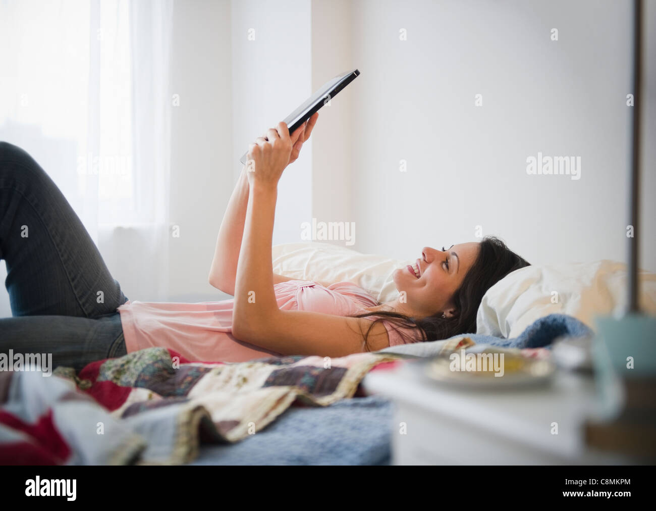 Brazilian woman using digital tablet in bed Stock Photo