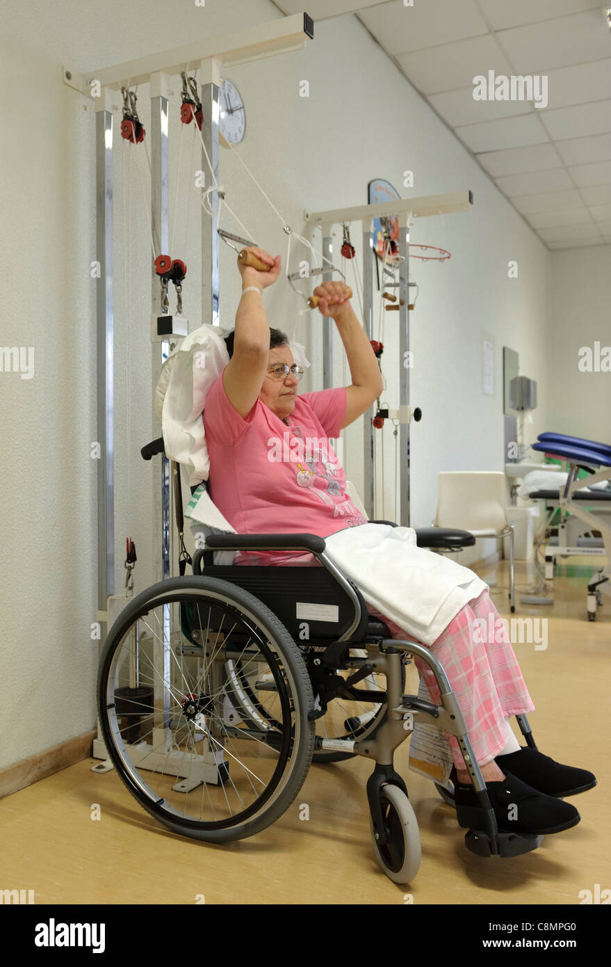 Woman on wheelchair doing physical rehabilitation exercises at hospital's physiotherapy gymn Stock Photo