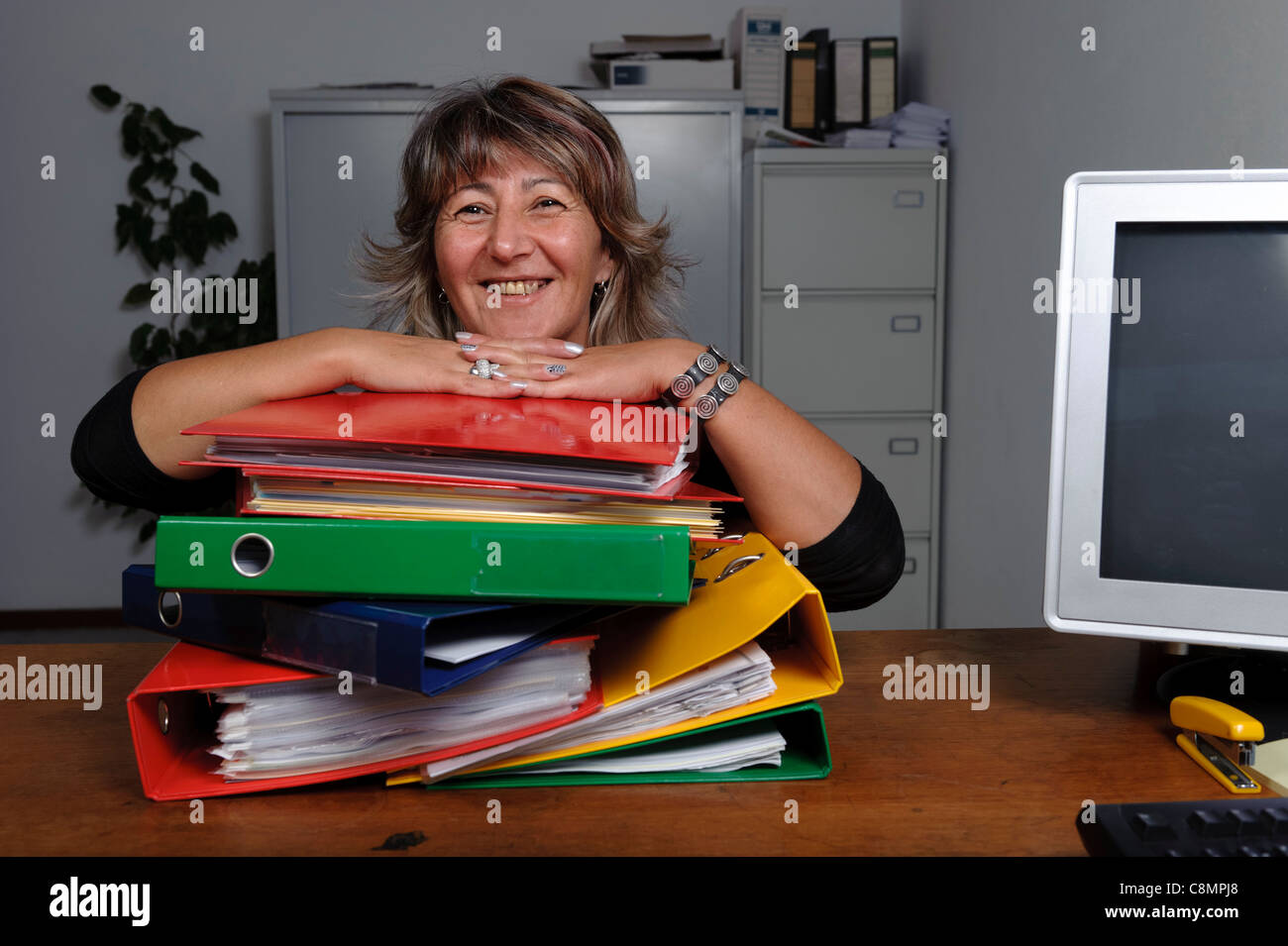 Female office worker on desk with stack of file folders on ring binders Stock Photo