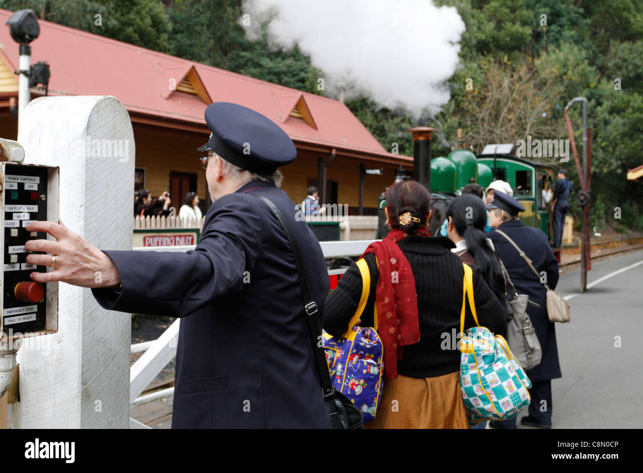 Train conductor operating old gate controller at Puffing Blly Lakeside station. Stock Photo