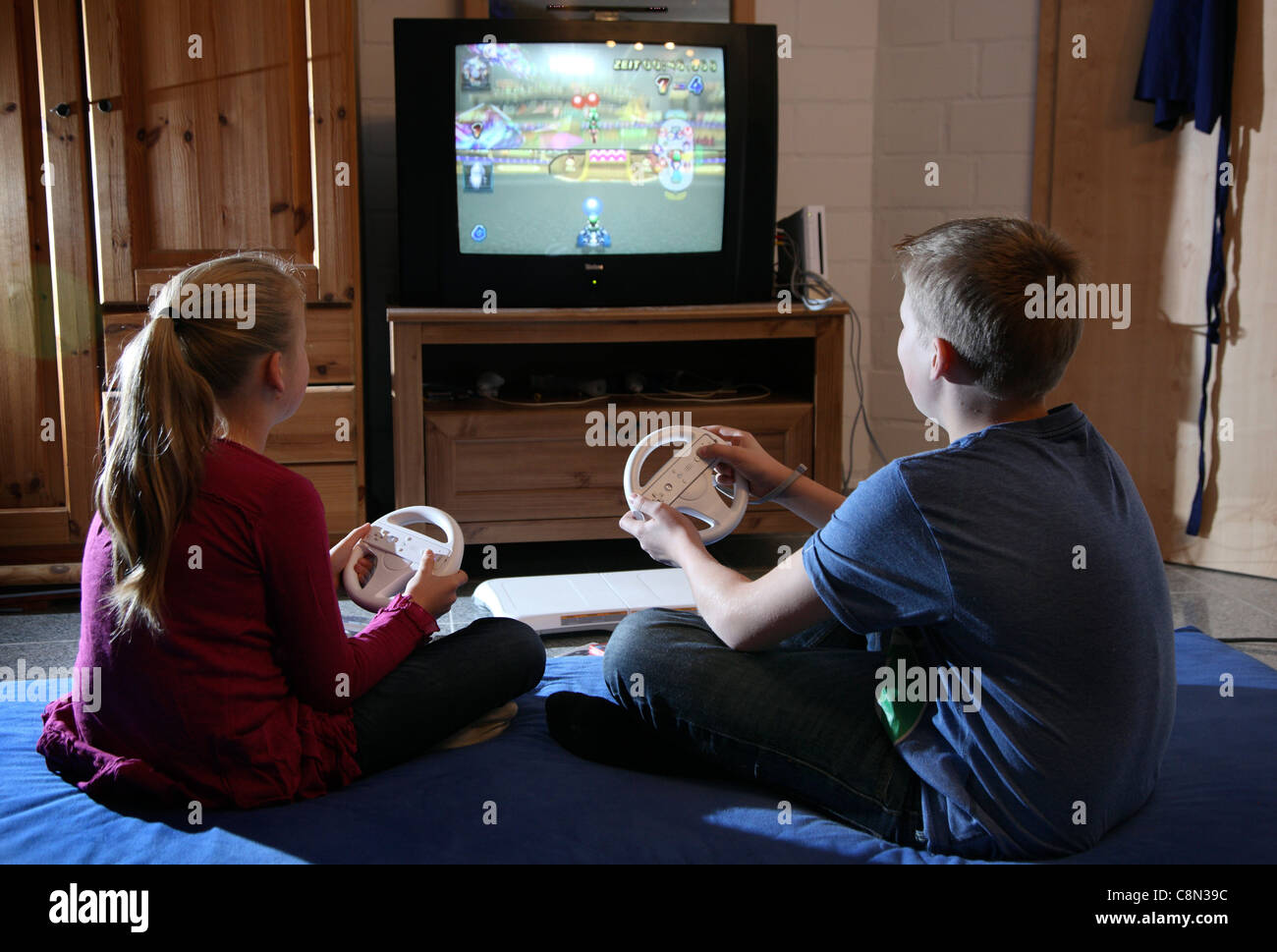Two kids, girl 10 and boy 13 years old, playing at home with a WII ...
