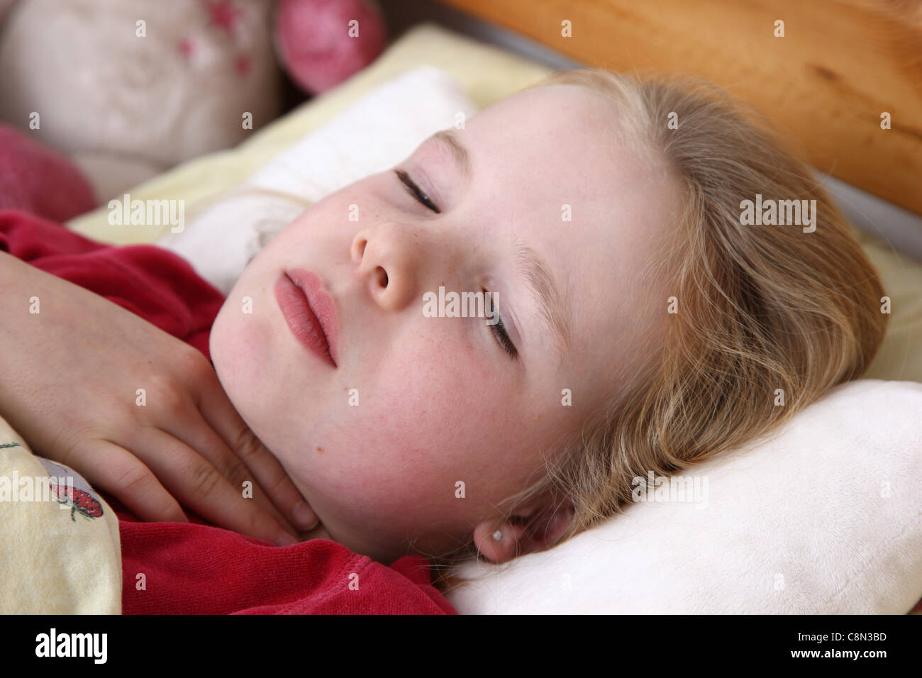 Young girl, 10 years old, lies sick in bed with a flu. Having a sore throat. Stock Photo
