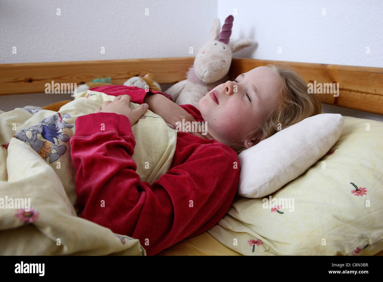 Young girl, 10 years old, lies sick in bed with a flu. Having a sore throat. Stock Photo