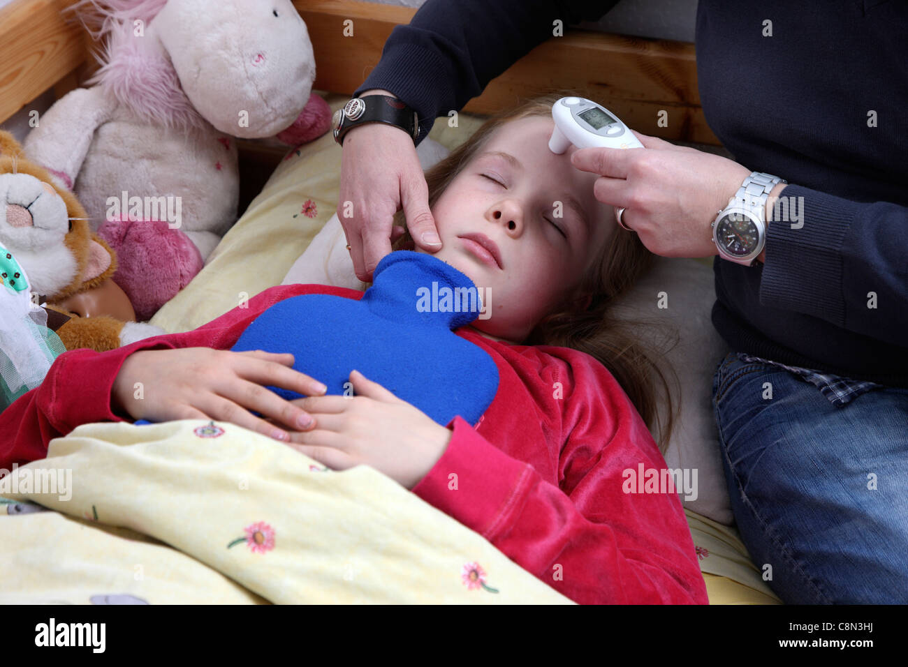Young girl, 10 years old, is sick in bed, gets help and care from her mother. Stock Photo