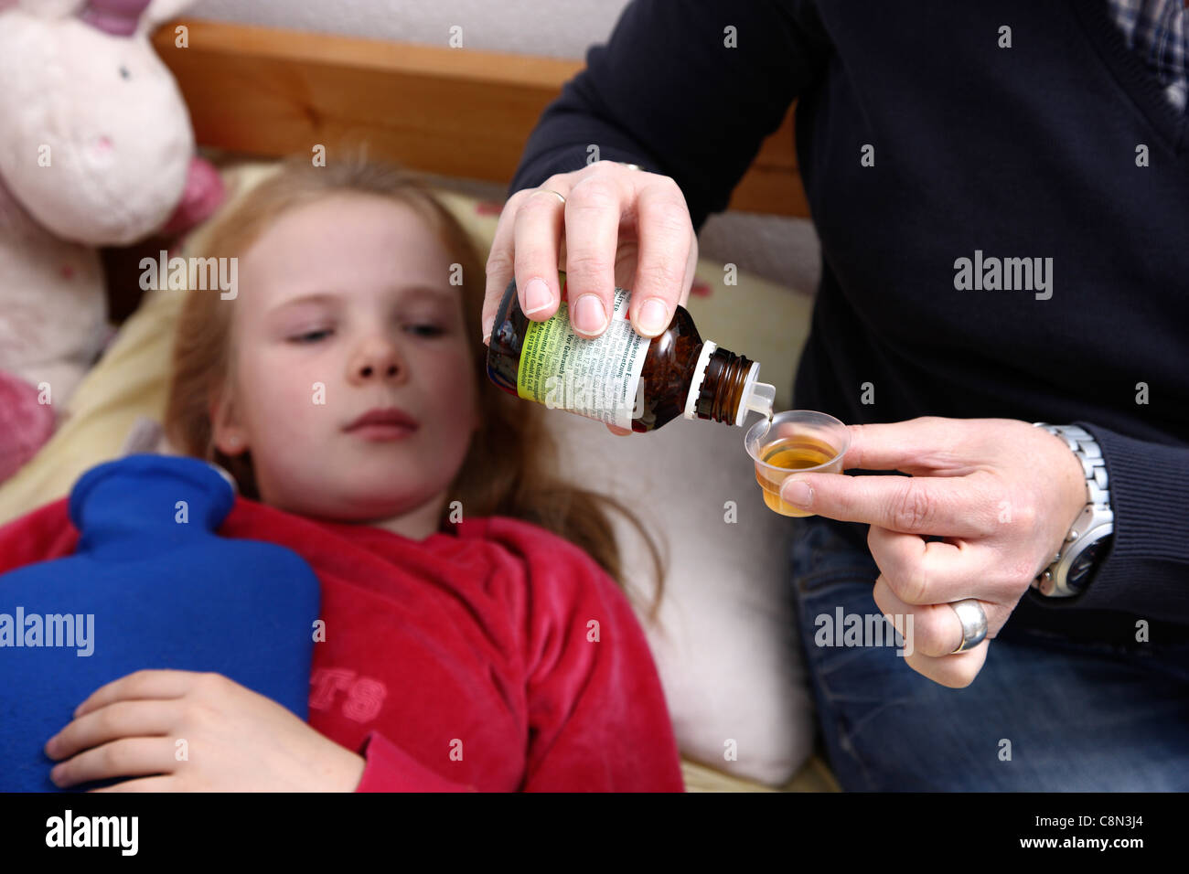 Young girl, 10 years old, is sick in bed, gets help and care from her mother. Stock Photo