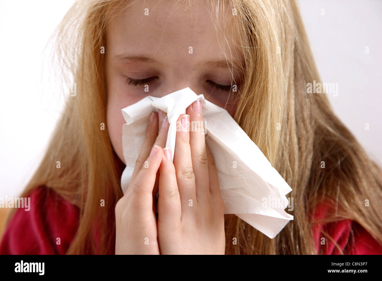 Young girl, 10 years old, lies sick in bed, at home, with a flu, sneezing. Stock Photo