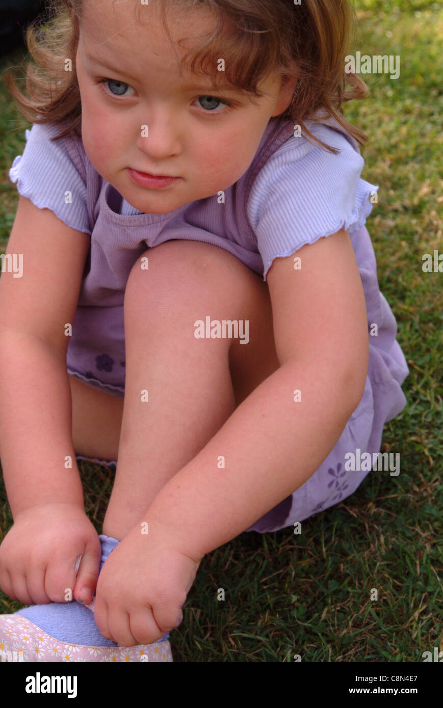 Little girl putting her shoes on outside Stock Photo