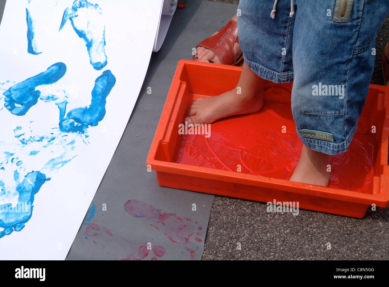 Nursery child painting footprints by walking in paint with bare feet