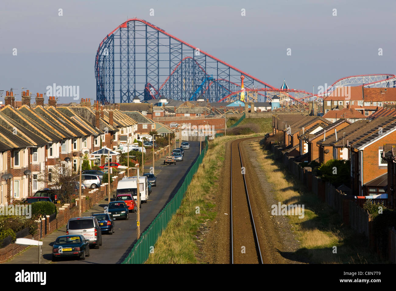 Railway line and rows of houses overshadowed by 'The Big One' roller coaster in Blackpool's Pleasure Beach Stock Photo