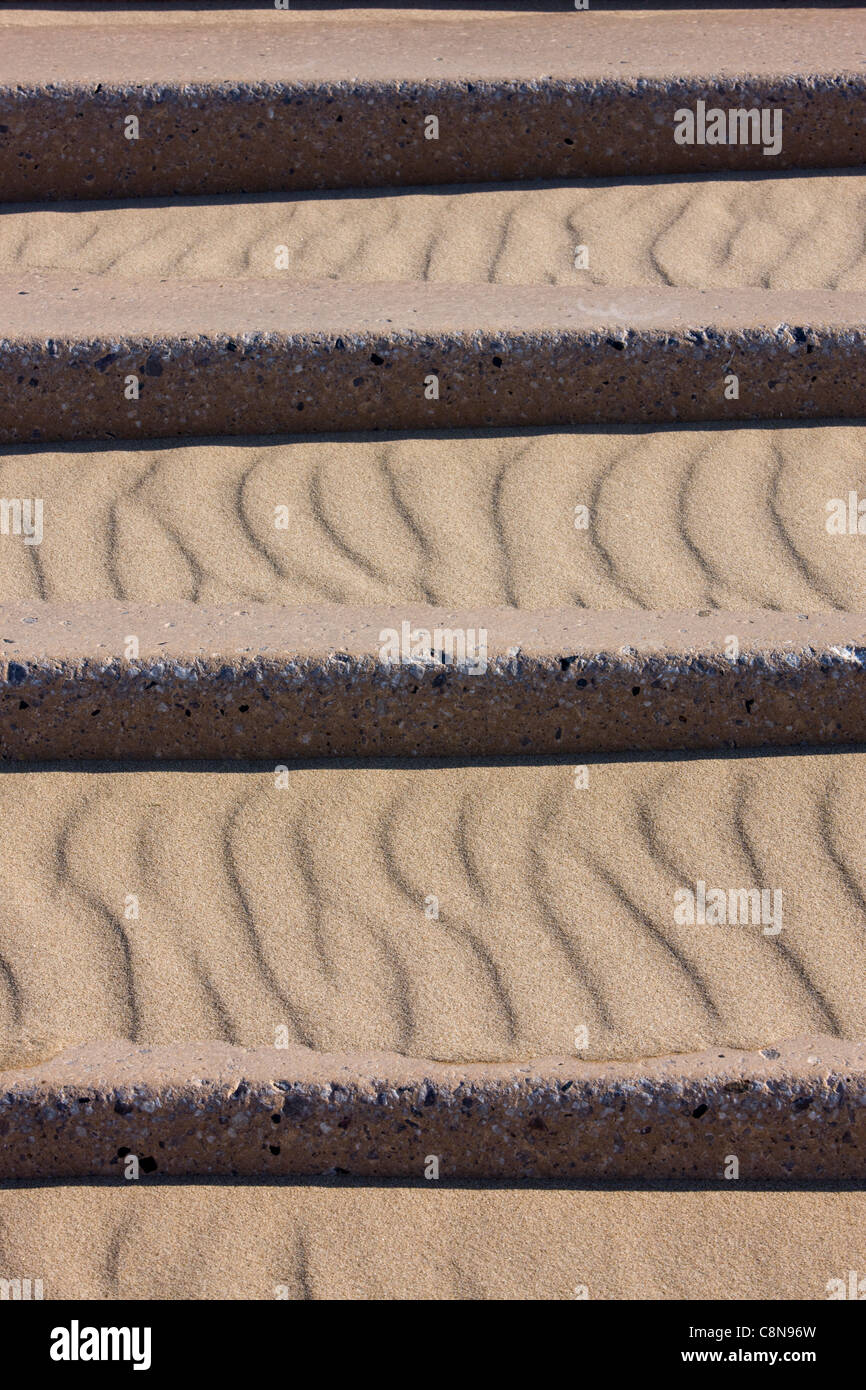 Patterns in the sand drifting on the concrete steps leading down to the beach in Blackpool, UK Stock Photo