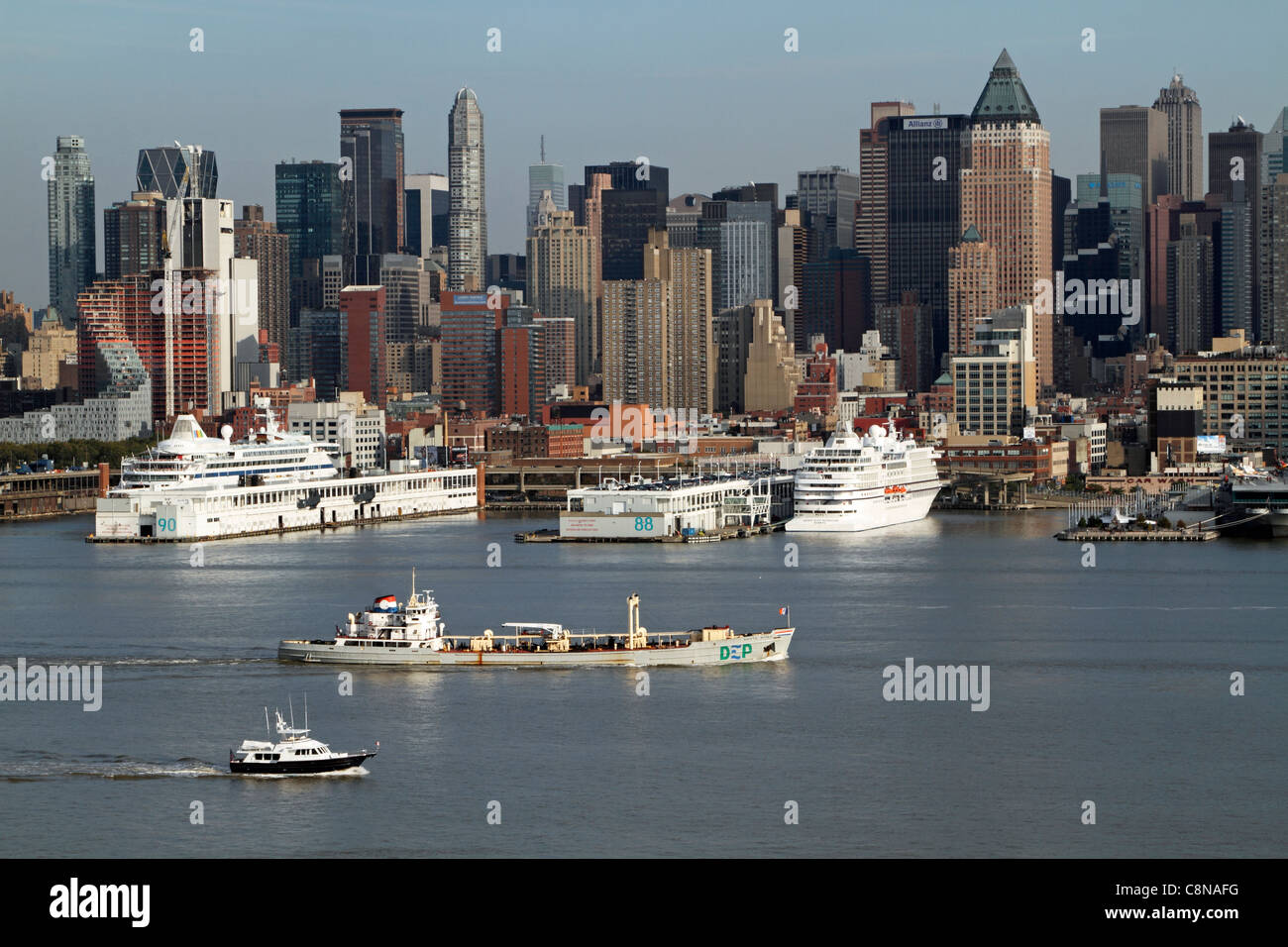 Boats on the Hudson River passing docked cruise ships.. The boat in the middle of the river is a sludge boat. Stock Photo