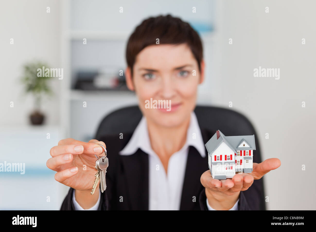 Woman showing a miniature house and a key Stock Photo - Alamy