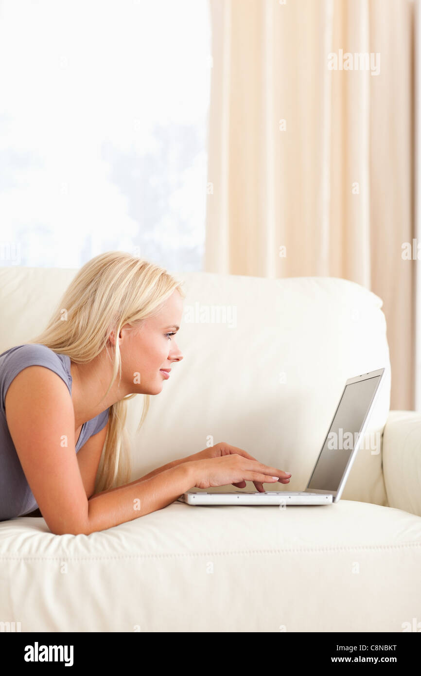 Woman lying on a couch while using a laptop Stock Photo - Alamy