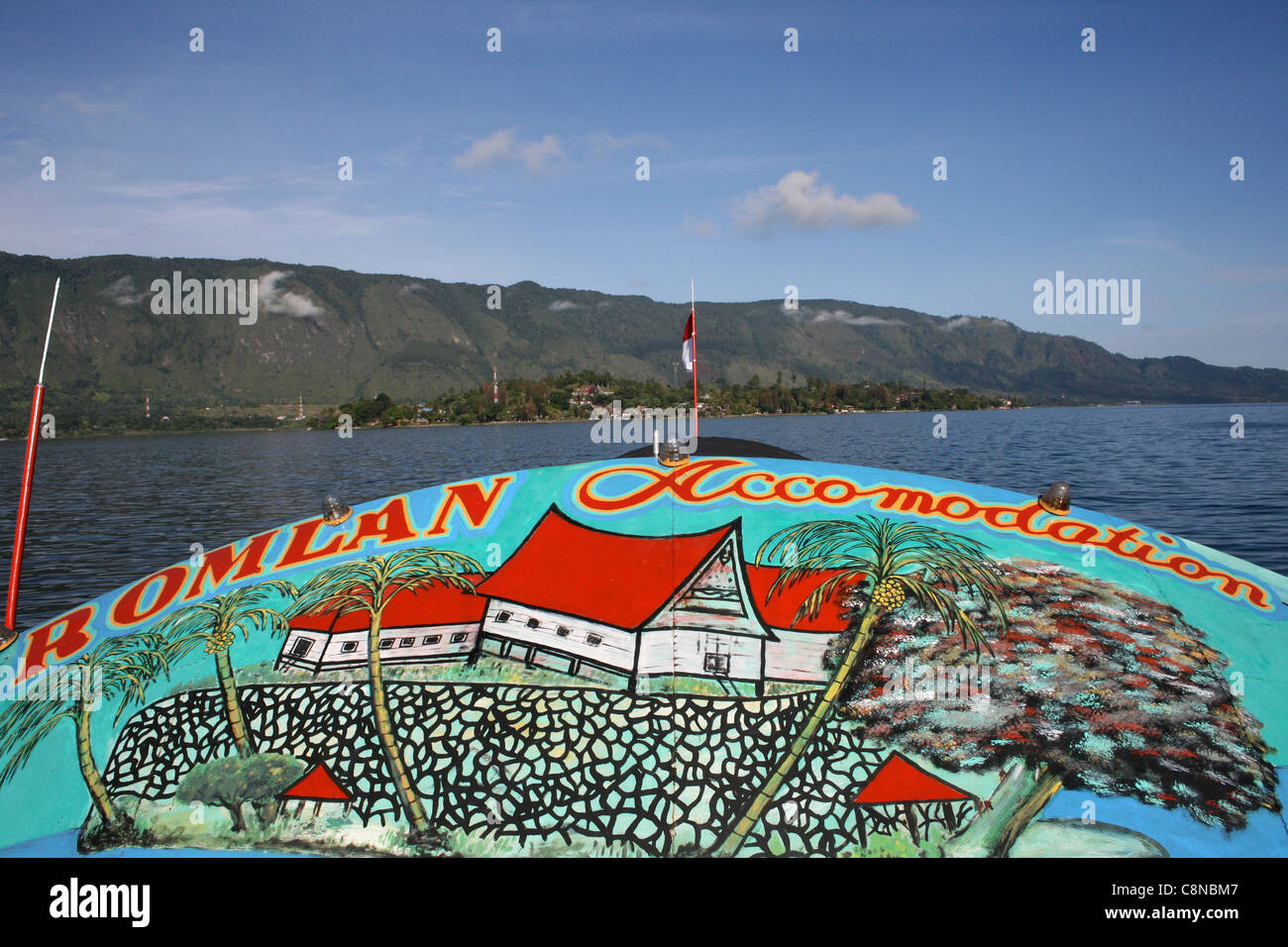 Brightly Painted Boat Sailing On Lake Toba Approaching Samosir Island, North Sumatra Stock Photo