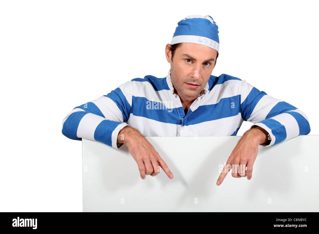 Man in a mock prisoner outfit with a board left blank for your message Stock Photo
